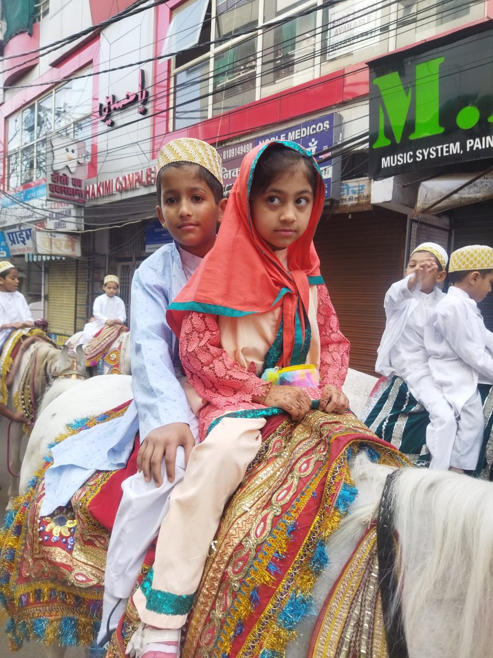 रंग बिरंगी पोशाकों में घोड़े पर बैठे बच्चे।